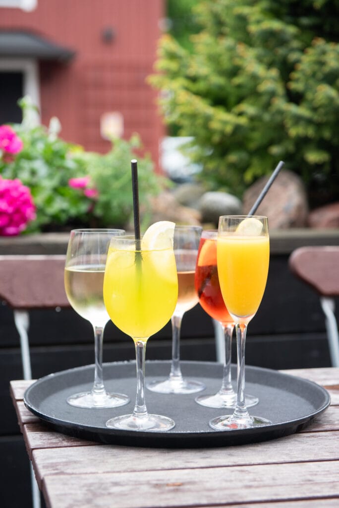 Neljä värikästä cocktailia tarjottimella ulkona pöydällä.