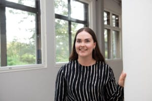 Nainen hymyilee ikkunan edessä toimistossa