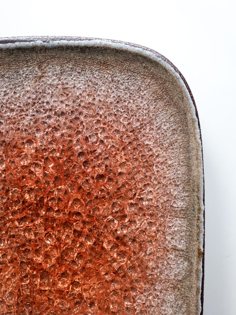 Ruskea, rosoinen savilautanen keraamisella pinnalla