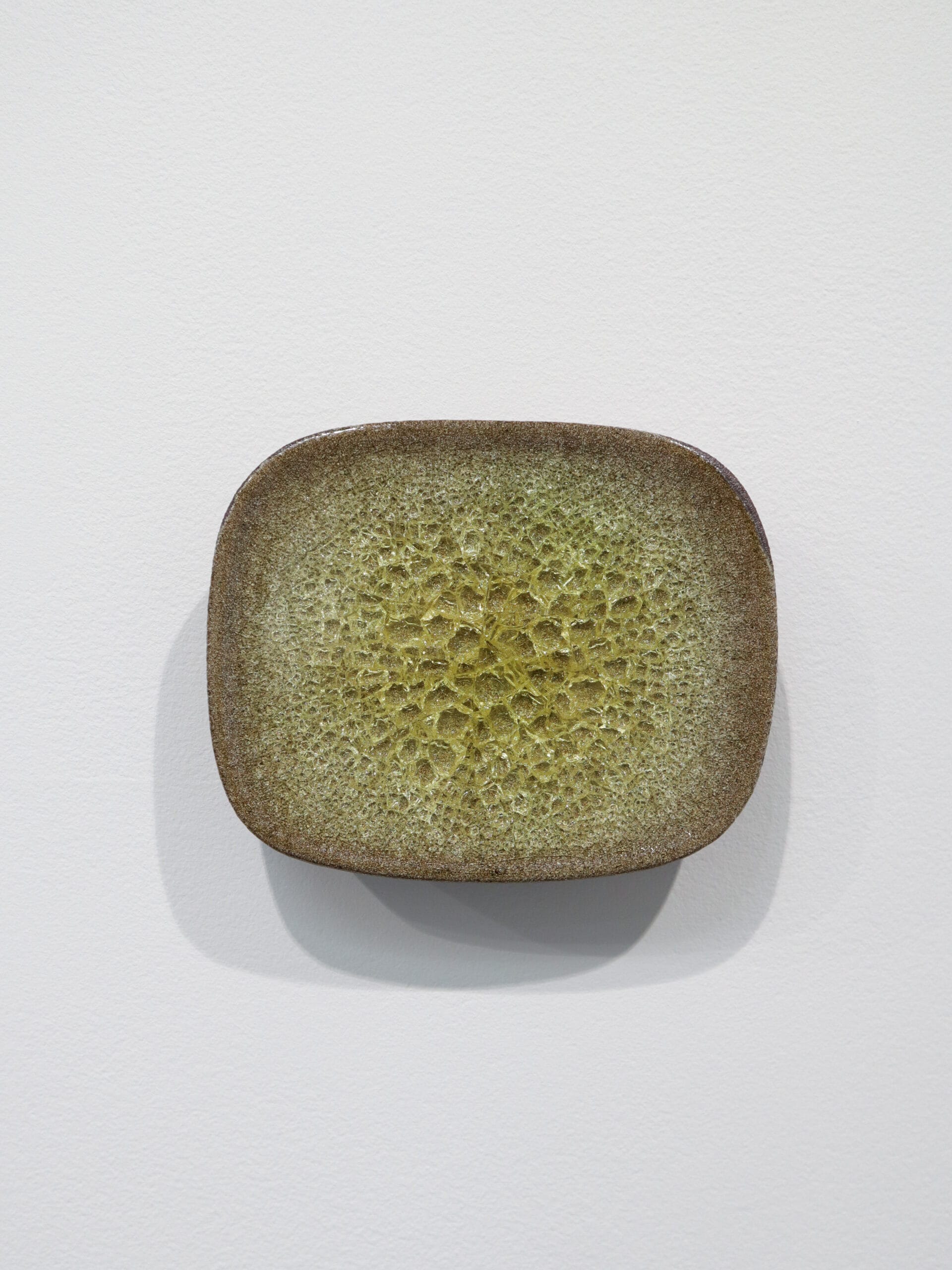 Oliivinvihreä neliönmuotoinen keramiikkavati valkoista taustaa vasten.
