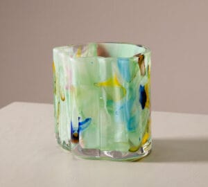 Monivärinen lasimaljakko pöydällä