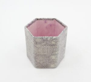 Koristeellinen kuusikulmainen purkki vaaleanpunaisella sisäosalla.