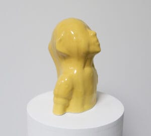 Keltainen veistos valkoisella alustalla.