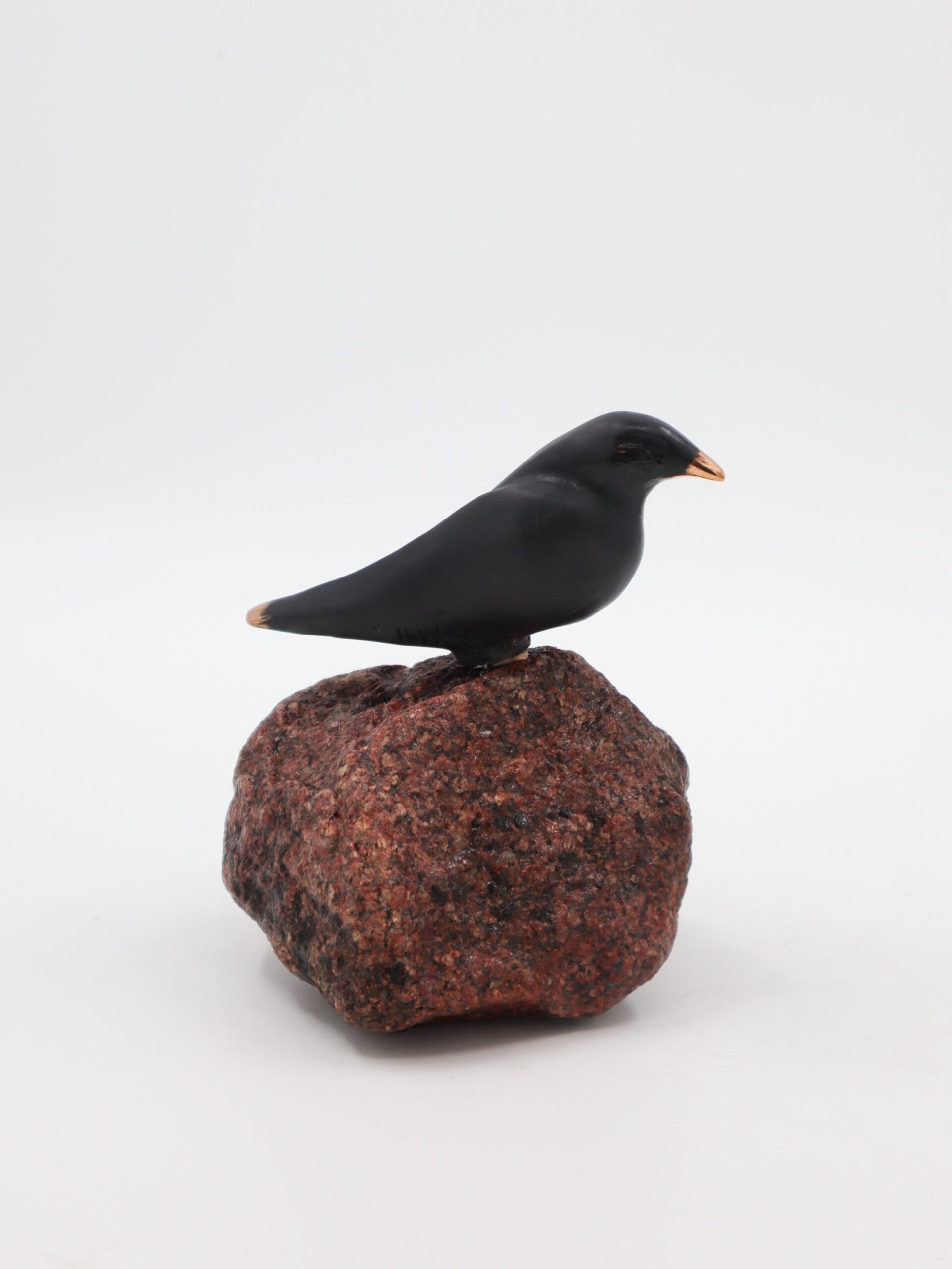 Musta lintuveistos punaisella kivellä