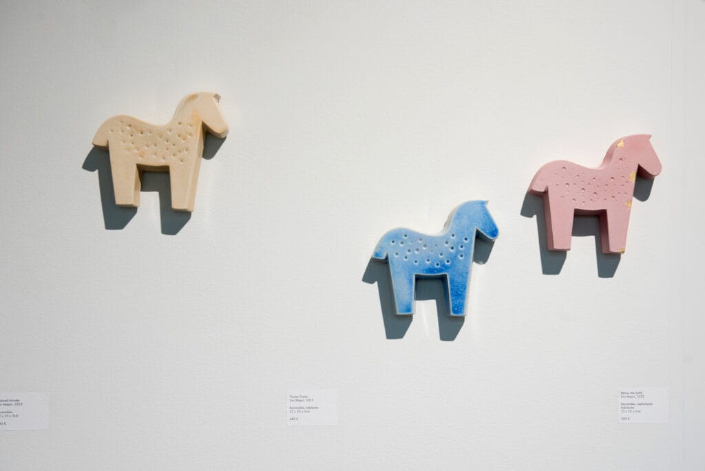 Kolme värikästä hevosta seinällä, taideteos.