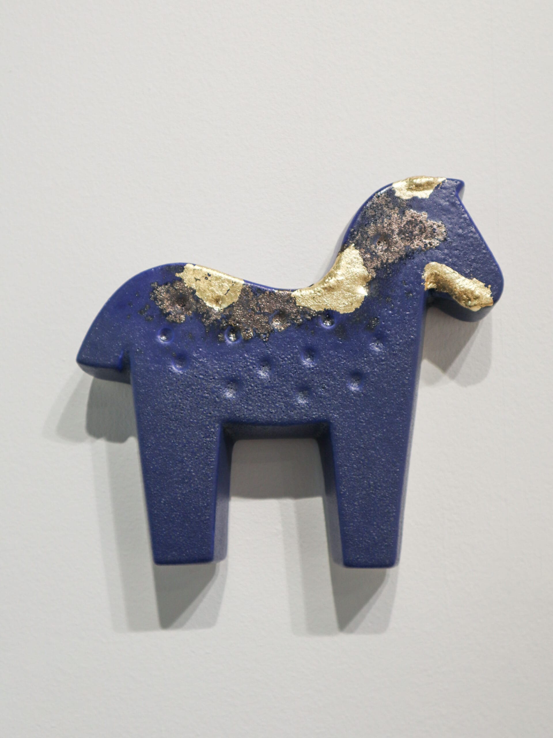 Sininen koristehevonen kultakoristeilla, seinäkokoelma.