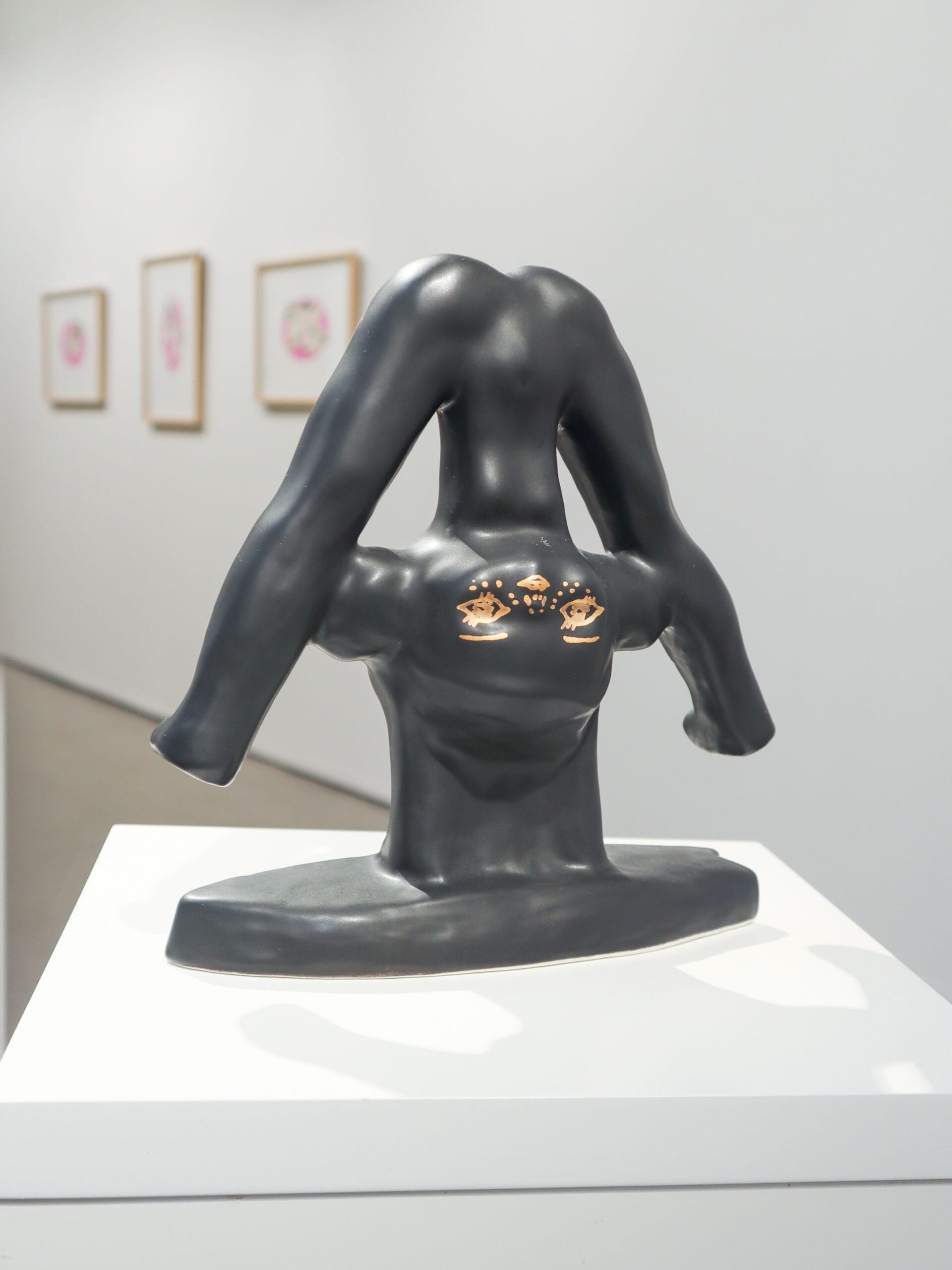 Moderni veistos gallerianäyttelyssä, tumma materiaali ja silmät.