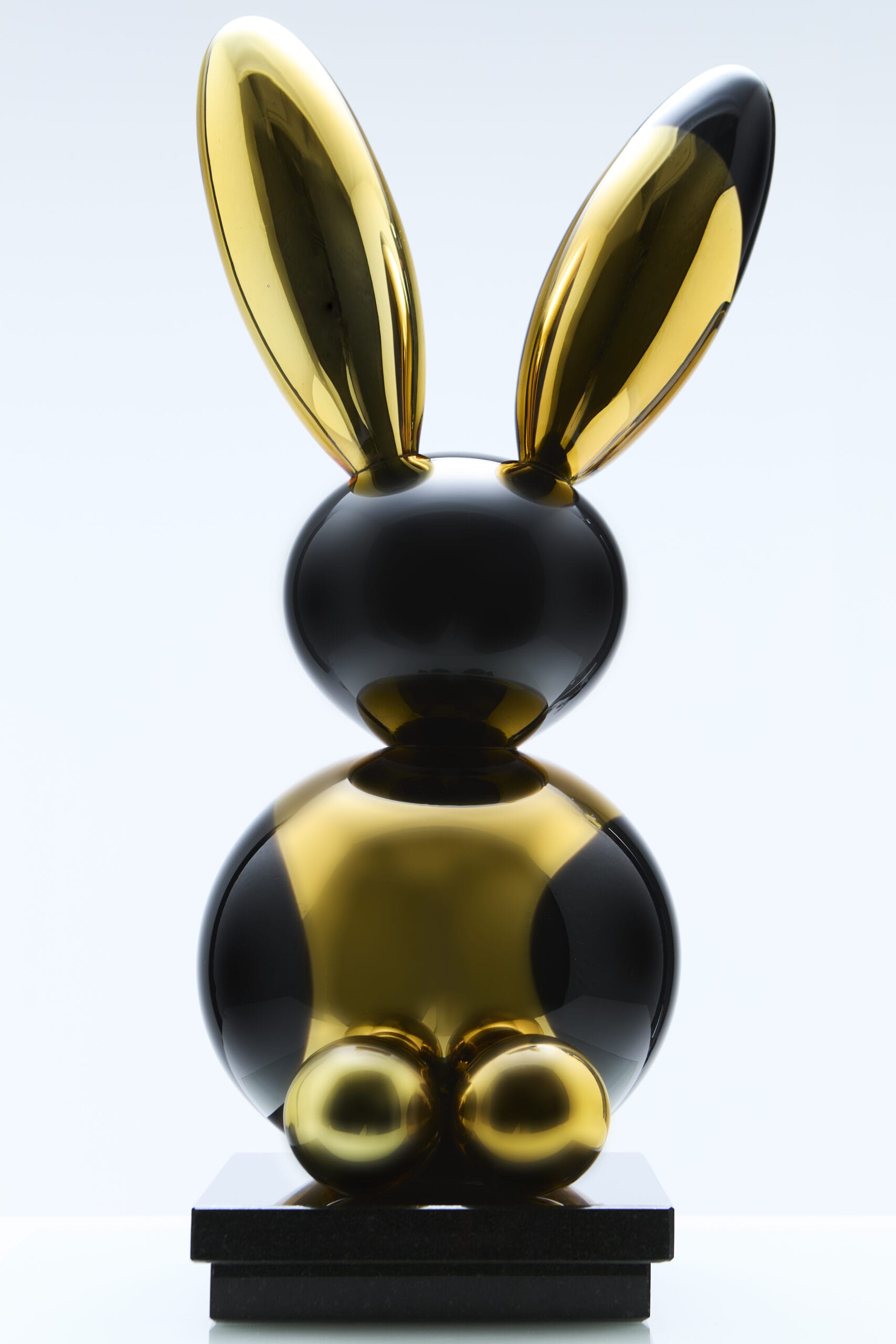 Kultainen ja musta jänisveistos marmorijalustalla.