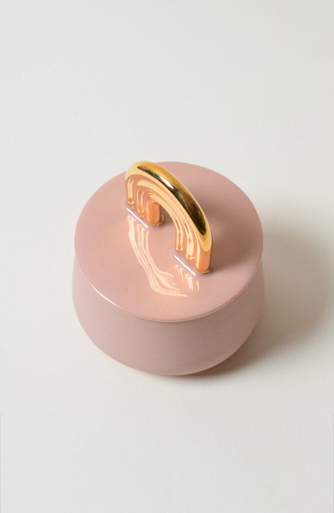 Vaaleanpunainen kannellinen astia kultaisella kahvalla