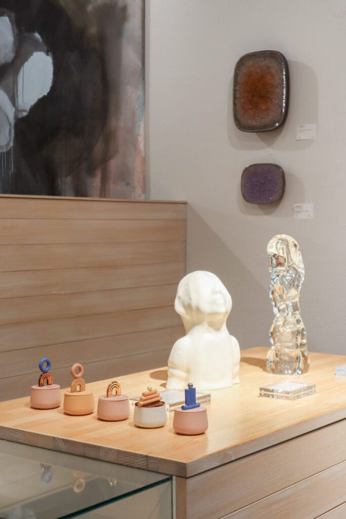 Veistokset esillä galleriassa puupöydällä.