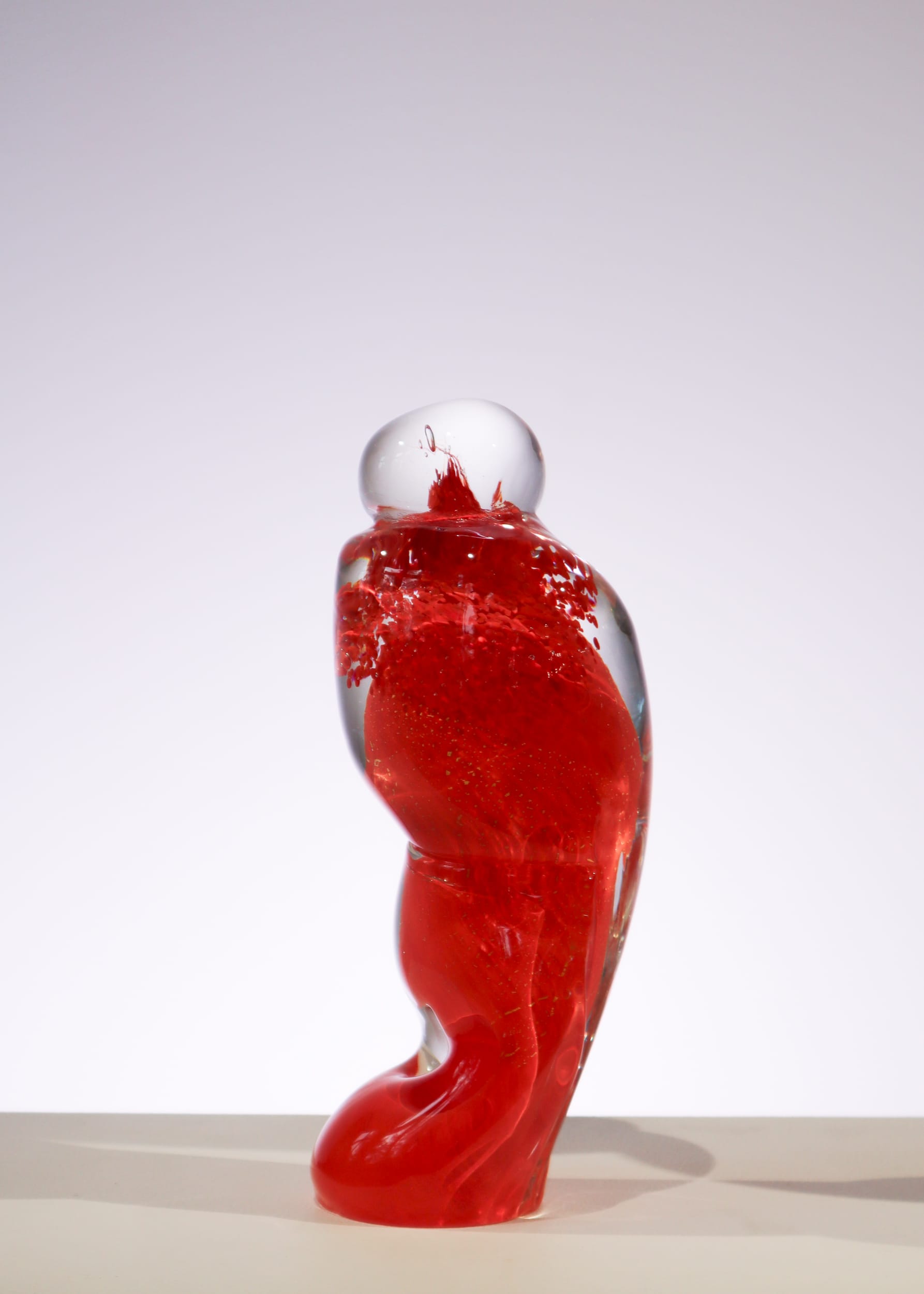 Punainen lasiveistos valkoisella taustalla