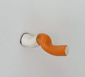 Oranssi ja valkoinen taideteos seinällä.