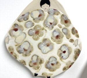 Keraaminen taideteos, kukkakuviolla ja ihmishahmolla.