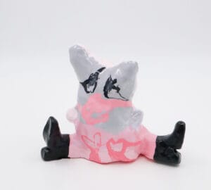 Vaaleanpunainen ja harmaa keraaminen hahmo mustilla saappailla.