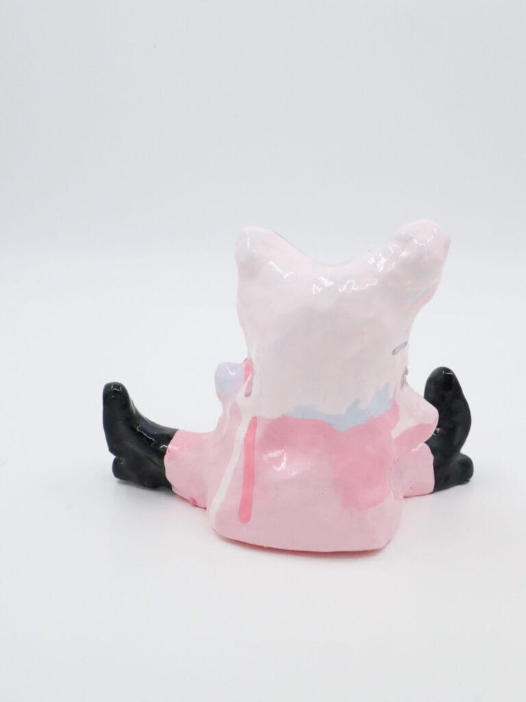 Vaaleanpunainen keramiikkafiguuri vaalealla taustalla.