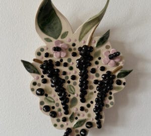 Keraaminen lehti, mustat marjat ja vihreät lehdet.