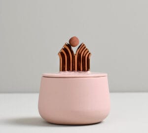 Vaaleanpunainen purkki kultakoristeella kannessa.