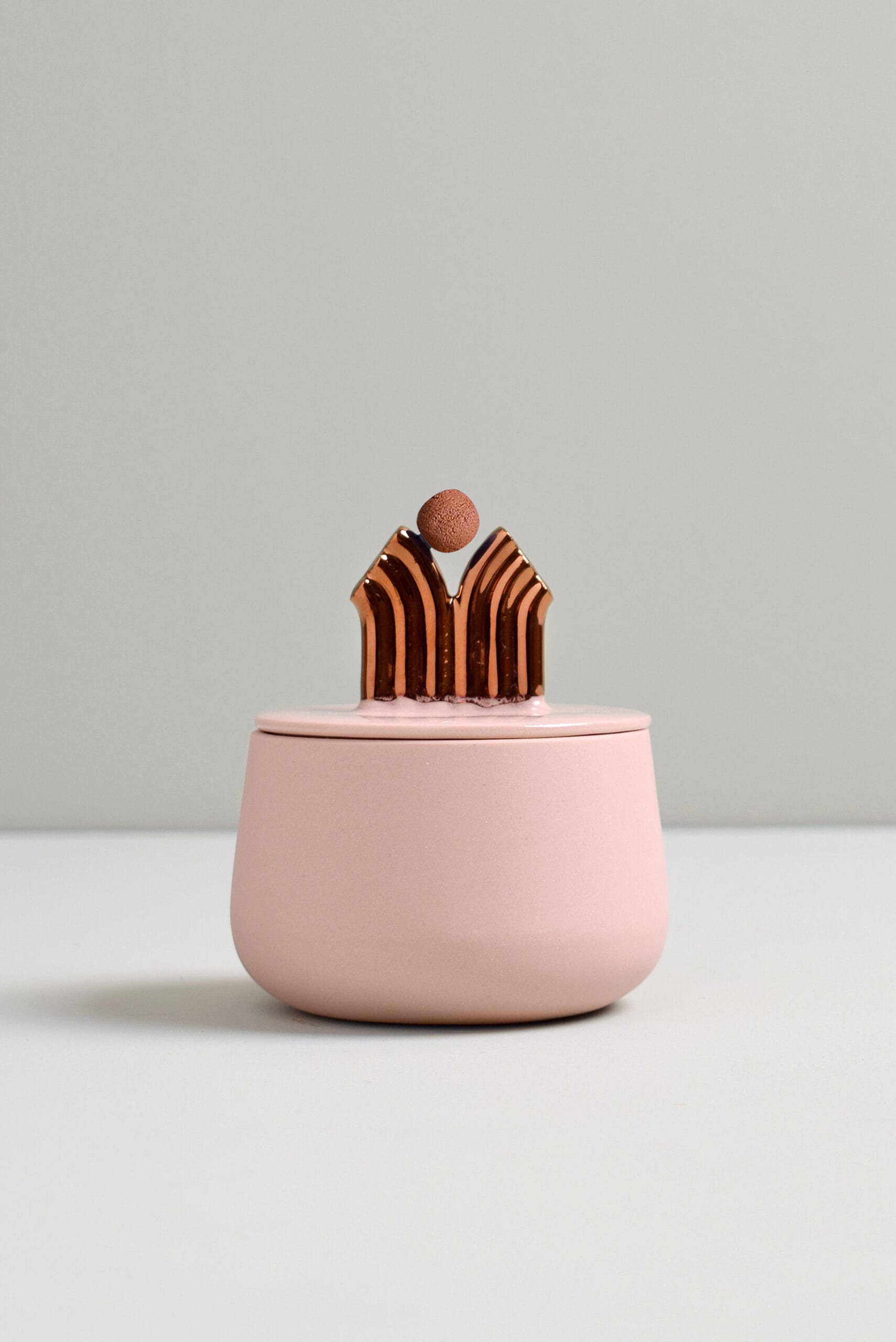 Vaaleanpunainen purkki kultakoristeella kannessa.