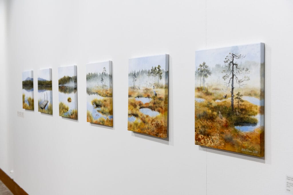 Maisemamaalauksia galleriassa: järviä ja metsiä syksyllä.