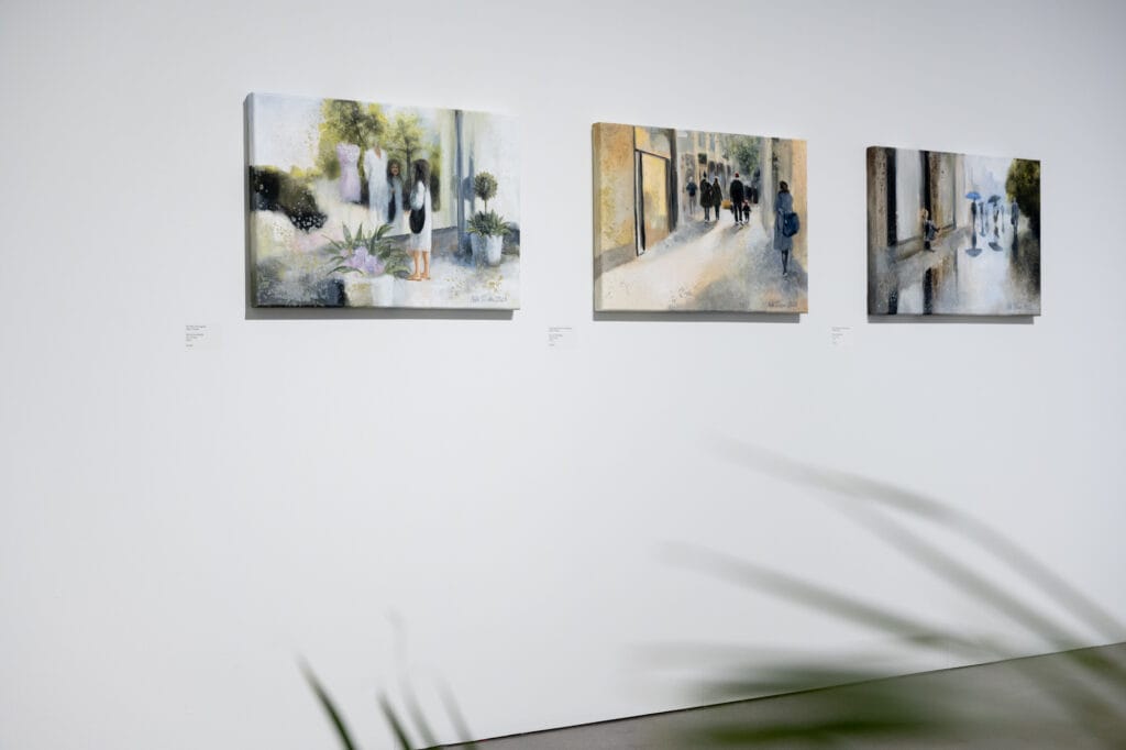 Kolme maalausta valkoisella galleriaseinällä